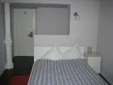 Cama individual con cabecero blanco, columna decorativa y lámpara de pared en la habitación